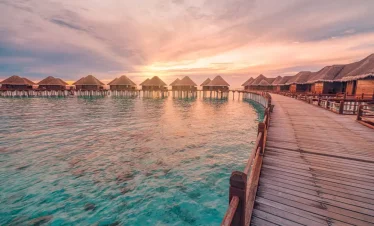 Sunset view over luxurious water villas in the Maldives, a romantic experience offered in Maldives tour packages from Bangladesh for couples and honeymooners
