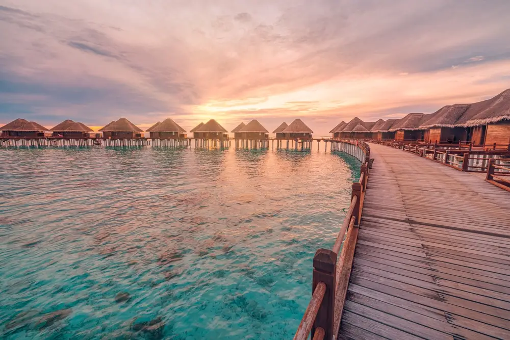 Sunset view over luxurious water villas in the Maldives, a romantic experience offered in Maldives tour packages from Bangladesh for couples and honeymooners